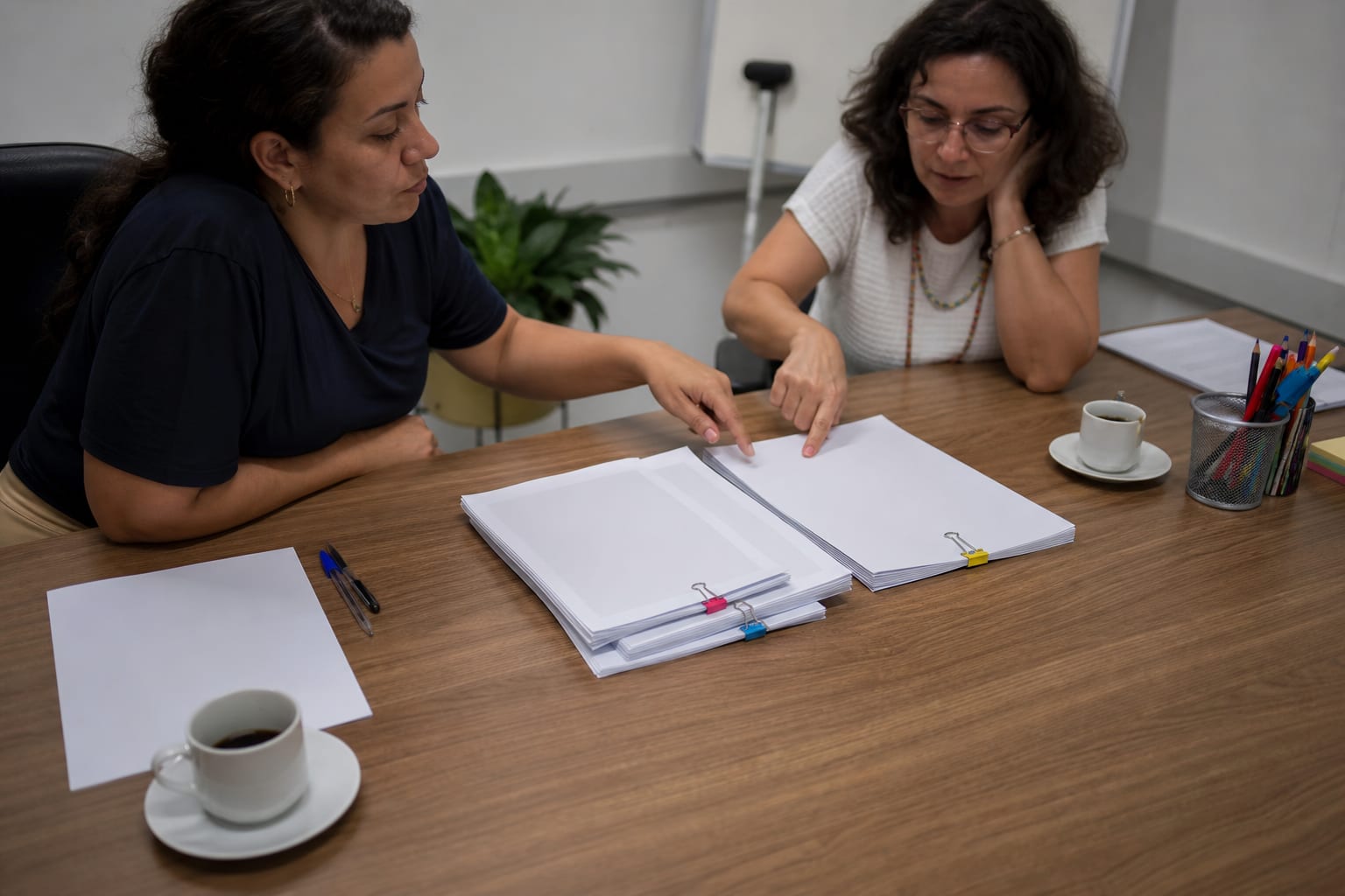 Reunião pedagógica com três conjuntos de documentos de planejamento sobre a mesa